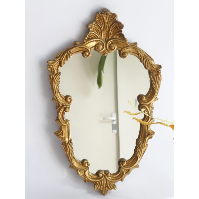Small baroque style mirror made in Italy. The mirror has a beautiful carved golden frame. It has ornaments all over and is...
