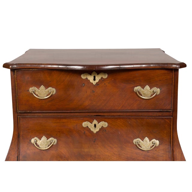 With a serpentine top and conforming bombe form case section with three drawers with brass bail handles, raised on bracket...