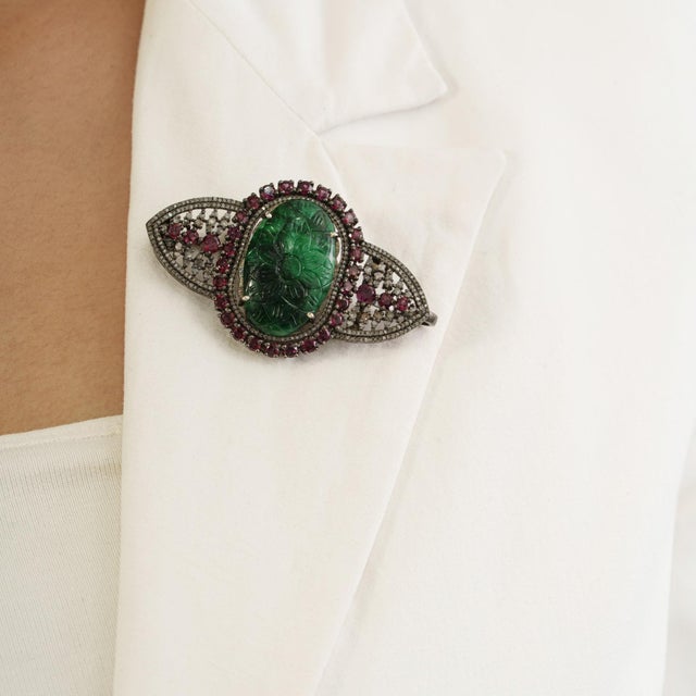The vintage-style ornate emerald, glass-filled ruby & diamond shield brooch pendant makes a distinctive statement with its...