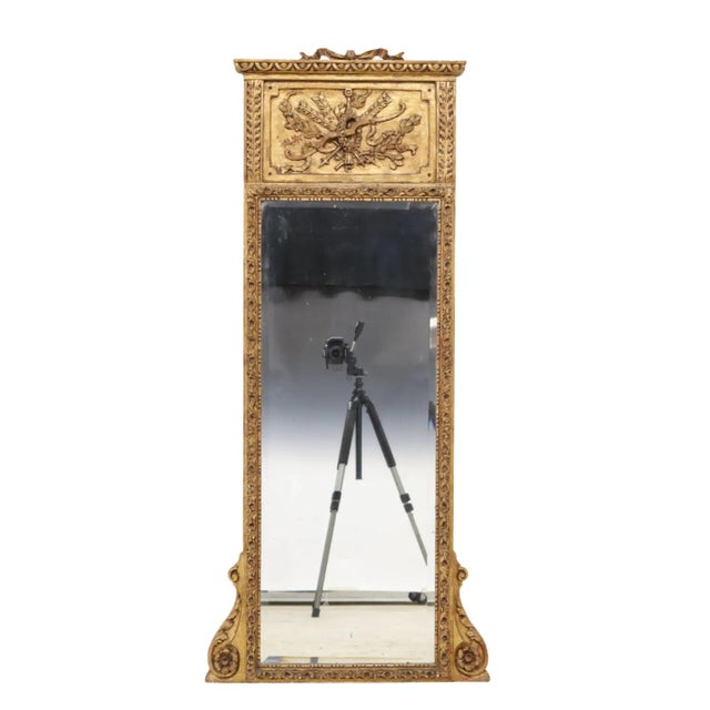 French Louis XVI style giltwood trumeau mirror, early 20th c., having ribbon crest, over carved panel with bow and arrow...