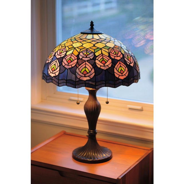 A spectacular and extra-large vintage Tiffany-style leaded glass lamp. The glass features a classic Art Nouveau peacock...