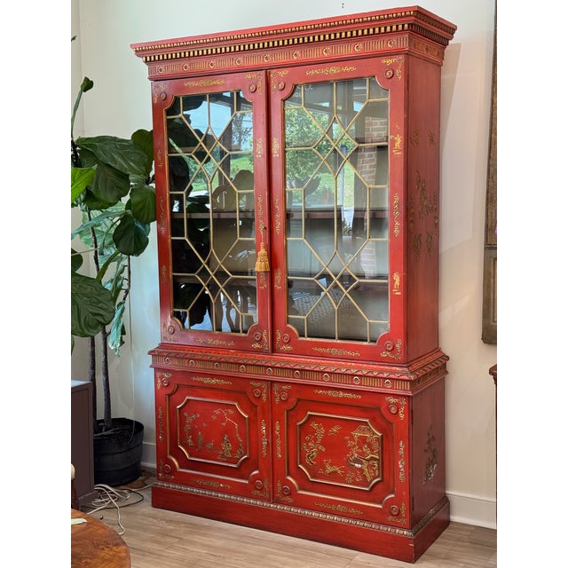 A pair of mid-20th century bookcase cabinets featuring a striking scarlet finish adorned with detailed chinoiserie...