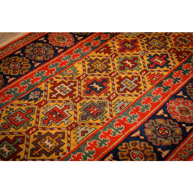 This antique Caucasian rug is a 3' 5" x 13' 7" runner featuring a striking yellow ground and bold, hand-knotted geometric...