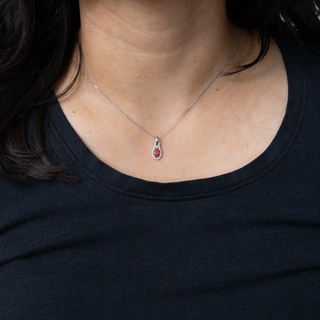 A 0.48-carat oval padparadscha sapphire glows at the centre of this solid 14K white gold pendant, surrounded by twenty-six...