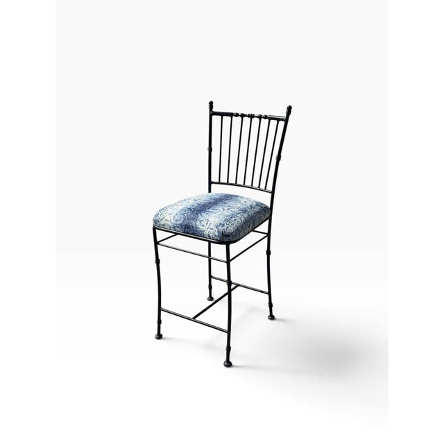 A slim, elegant counter stool in black wrought iron, shaped to mimic bamboo with ringed "node" accents on the legs and...