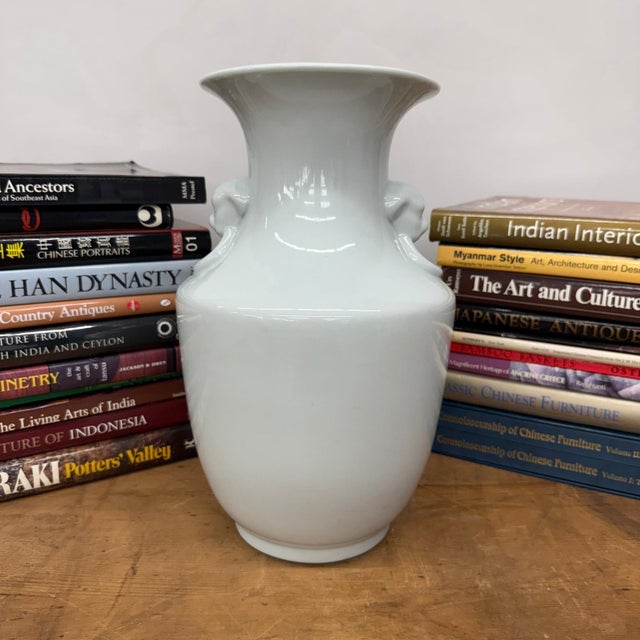 "About This Piece About This Piece Pure and serene, this vase gleams in a soft white glaze that enhances its elegant...