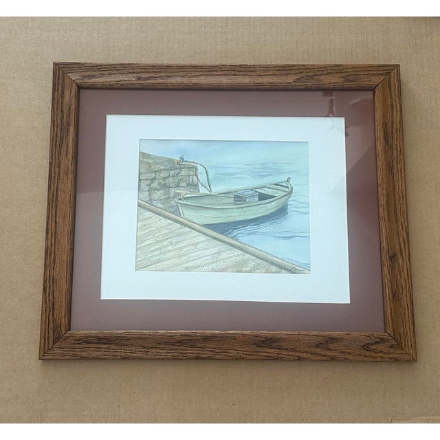 A serene original watercolor depicting a small green wooden boat moored at a stone dock, rendered in soft coastal hues....