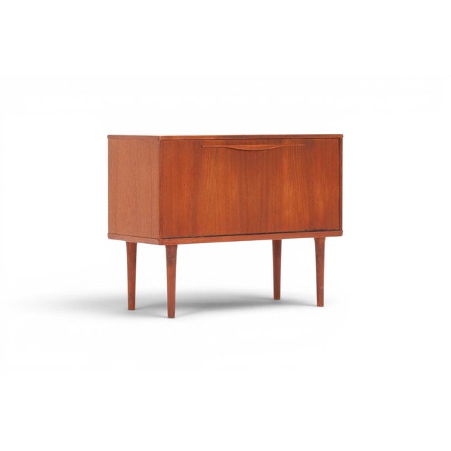 A charming and versatile 1960s Danish drop front cabinet by Lyby Møbler in warm solid teak. The drop front panel opens to...