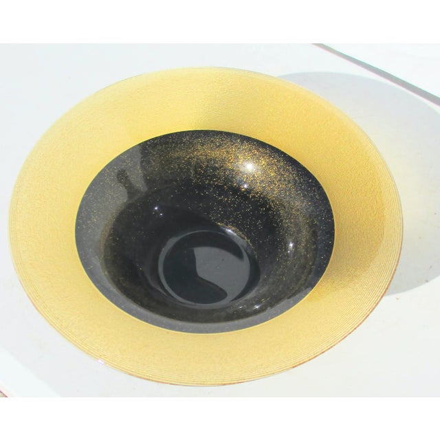 Sharp design black and gold amber-colored glass center bowl. Smooth inner surface with a spun texture outer walls in a...