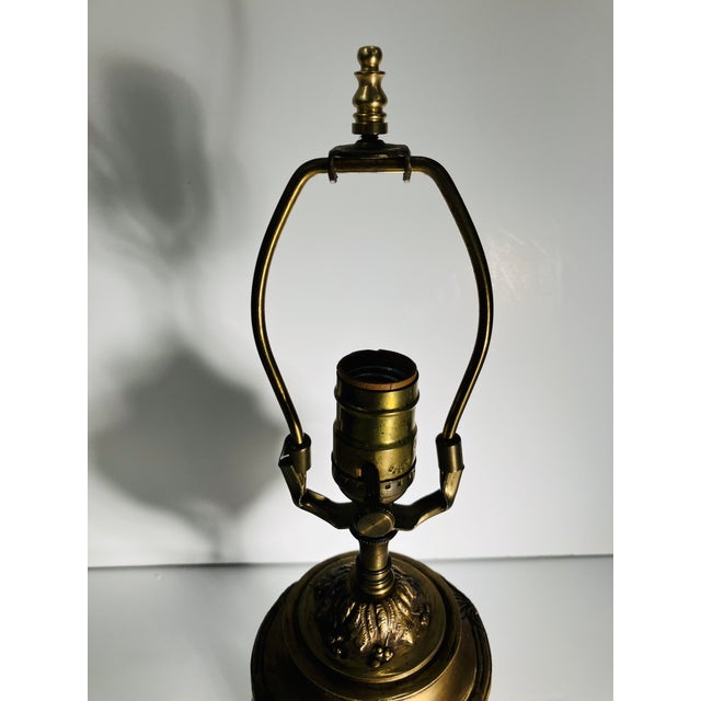 This bronze lamp is in the style of the French Empire . Three cabriolet legs with claw feet support a urn with floral...