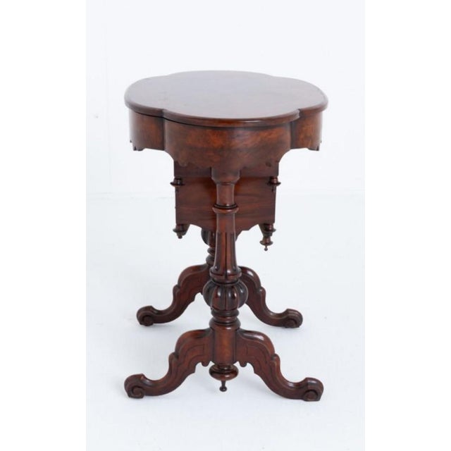 Victorian burr walnut sewing table. Circa 1860 This sewing table is of an oval form. The top having marquetry inlays and...