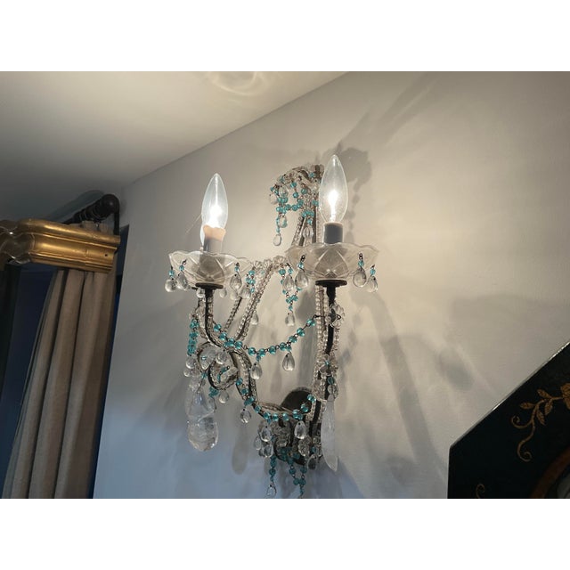 A charming pair of highly decorative three-light wall sconces featuring scrolling metal arms embellished with clear...