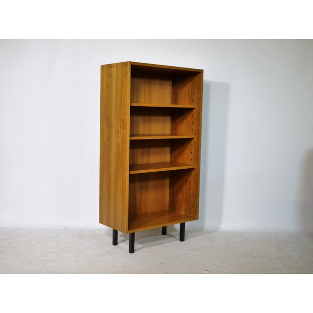 Minimalist walnut bookcase from Germany - 1960s. Four height-adjustable shelves in a straight frame on black legs. Width...