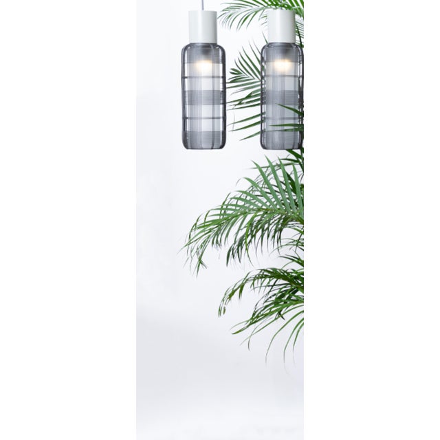 This handwoven galvanized iron pendant light wraps a slender oval cage around an elongated inner diffuser, finished with a...