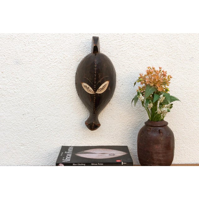 Discover the captivating allure of authentic African art with this vintage hand-carved wooden mask. Imbued with a rich...
