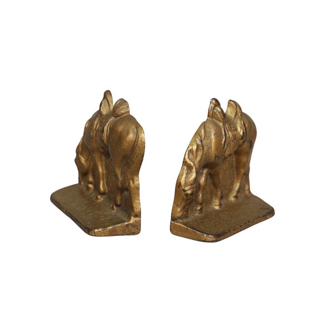 A pair of western style cast iron book ends. Cast in the shape of grazing saddled horses, in a gold brass finish. Details...