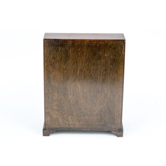 An antique salesman sample of an English mahogany bureau desk with visible dovetail joinery, a slanted fall-front writing...