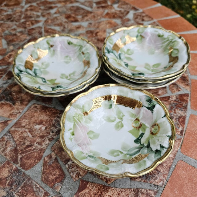 An elegant set of six ornate porcelain bowls, with a hand painted lovely floral pattern in soft pink and greens. They are...