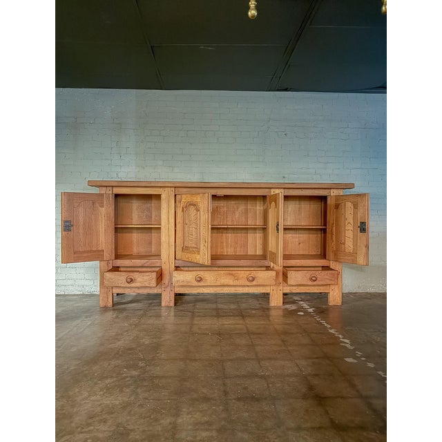 This Mid 1900s rustic French light oak paneled sideboard showcases the warmth and character of beautifully aged oak. The...
