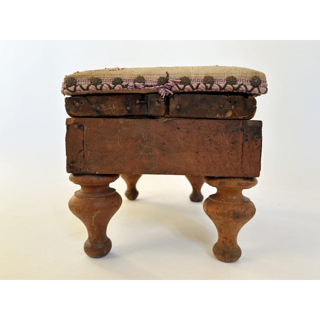 Here is a beautiful, primitive antique needlepoint footstool with turned wood feet and nailhead upholstery trim. This...