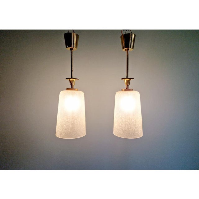 Pair of Mid Century pendant lights in brass with transparent crackled glass, 1950s-60s. Each of the pendant lights has...