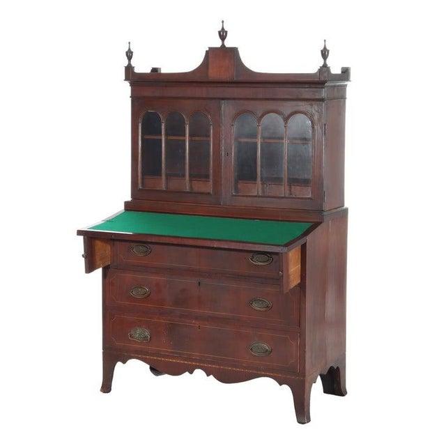 Offering a diminuative antique Federal Hepplewhite secretary with mahogany construction, inlay, upper bookcase over drop-...