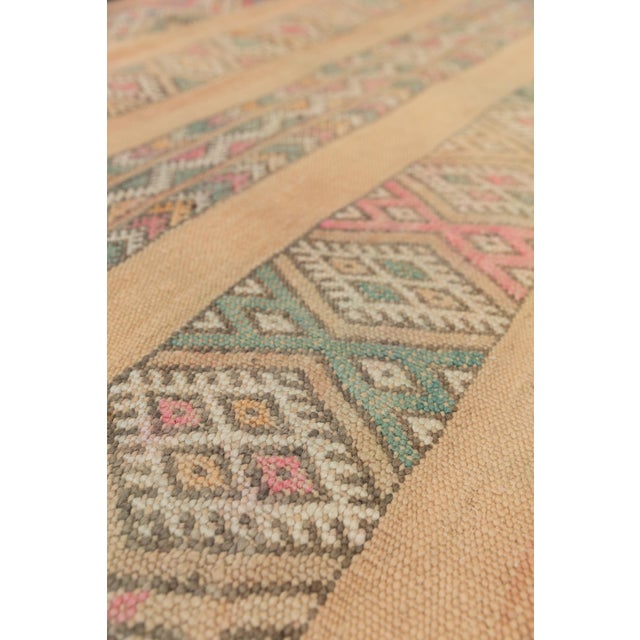 The DAWN vintage Zayane kilim rug showcases a rare palette of muted pastel hues woven into intricate geometric patterns....