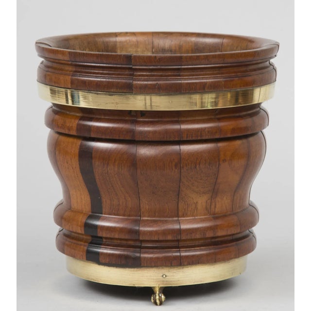 Turned walnut coopered jardiniere with brass bands and three brass paw feet. Beautiful graining in the walnut.