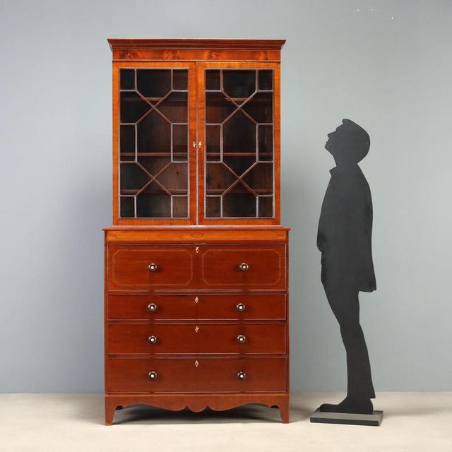 Early 19th-century English mahogany bookcase, enhanced with elegant maple inlays and ebony and maple stringing. The upper...