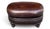 This distinctive vintage oval ottoman is upholstered in rich brown leather with a beautifully developed natural patina,...