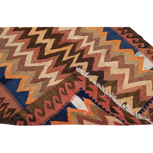 Beautiful vintage Turkish Kilim hand-knotted wool rug with a brown field. This piece has a rust frame and multicolor...