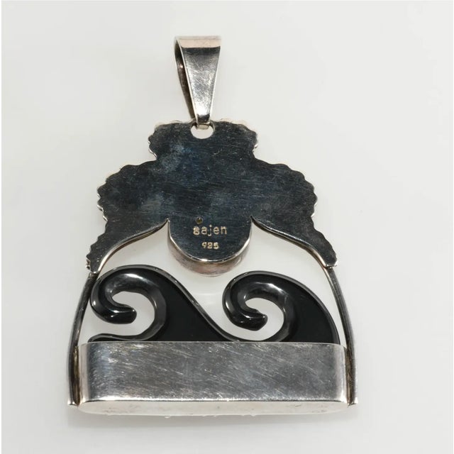 Large pendant with made of sterling silver set with a carved goddess face so popular in Sajen designs. The dark waves...