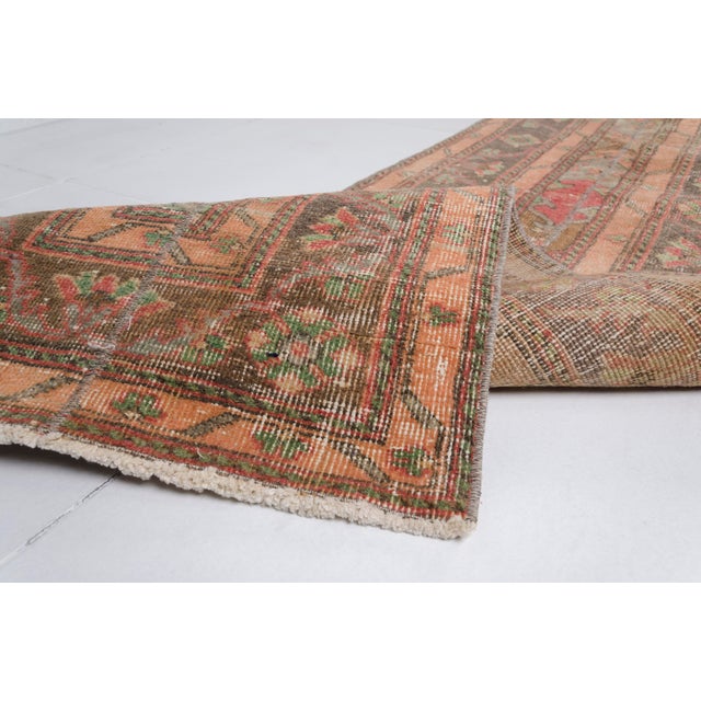 This is a vintage Turkish Oushak rug from the Mid 20th Century. The piece was hand-knotted.