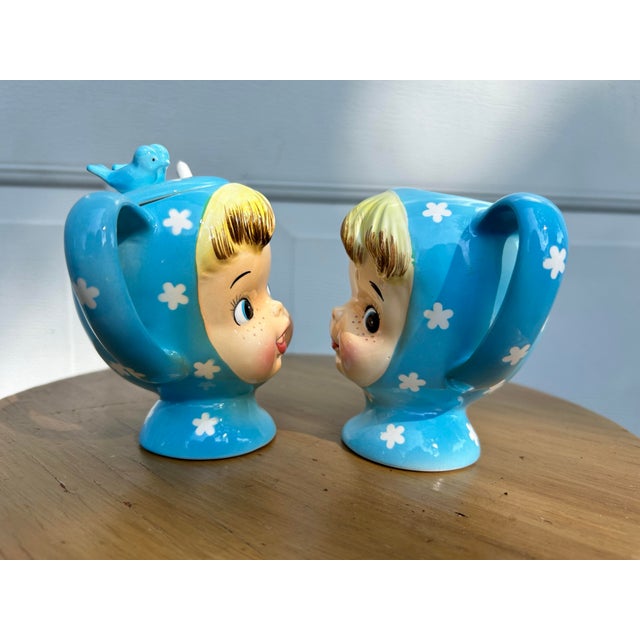 Cute as a button, these bright blue clad cheerful children are the Vintage Napco “Miss Cutie-Pie” sugar bowl with lid and...