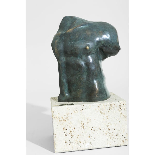Sculptural torso rests on a solid travertine plinth, balancing organic form with architectural weight. Marked, ‘Fili...