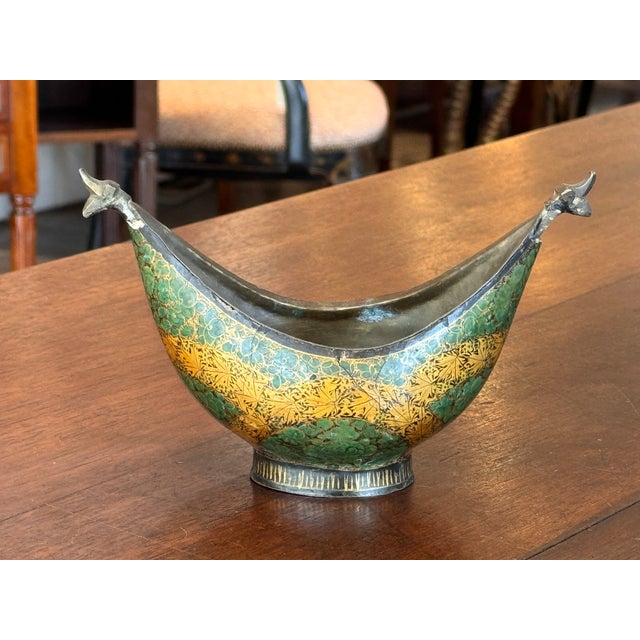 Enameled metal bowl with gently curved sides and stylized animal-form terminals. Hand-enameled floral and geometric motifs...