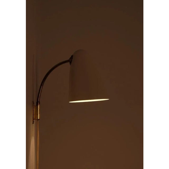 This pair of wall lamps model designed by the renowned Finnish designer Lisa Johansson-Pape. with its elegant curved arm...