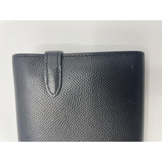 The wallet has a front flap and the Kelly trademark palladium turn-lock. This reveals a black leather inside with a...