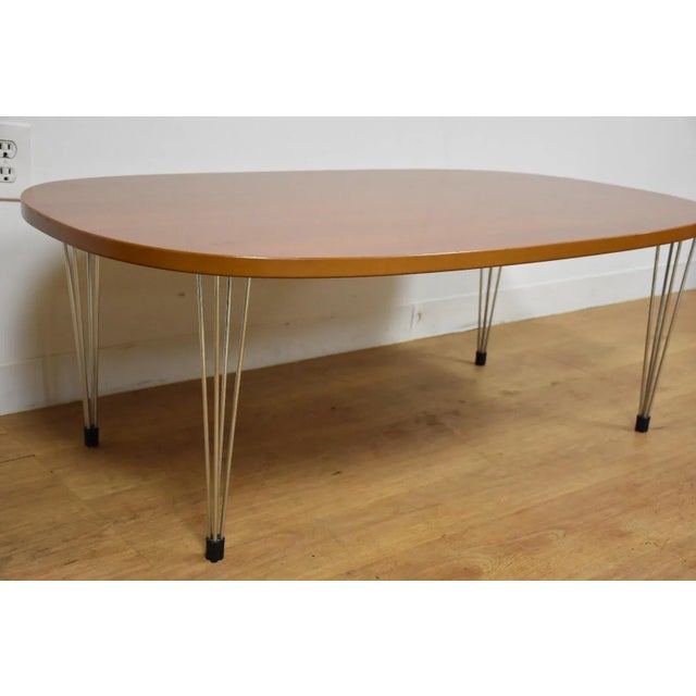 A mid century modern style Danish oval coffee table made of a cherry top and four legs which each consist of four chrome...