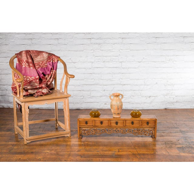 A Chinese Qing Dynasty period low kang cabinet from the 19th century, with carved scrolling apron and five drawers....