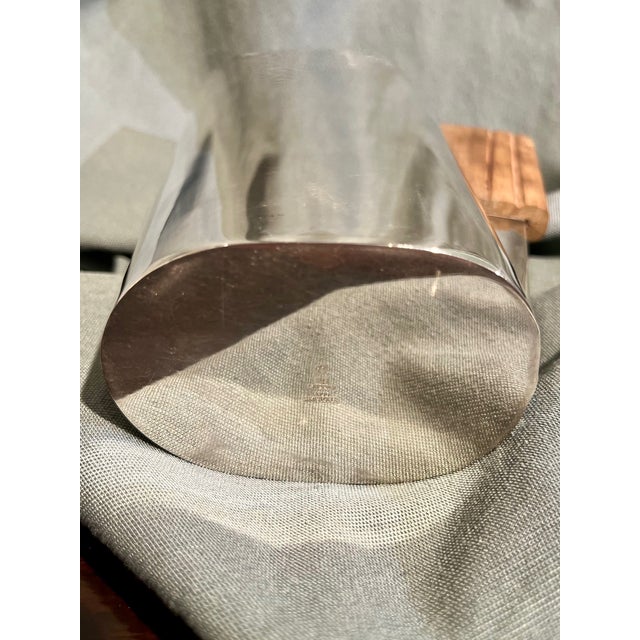 Stainless steel carafe with a natural Indian walnut handle. The jug is a single piece of folded sheet metal, with an...