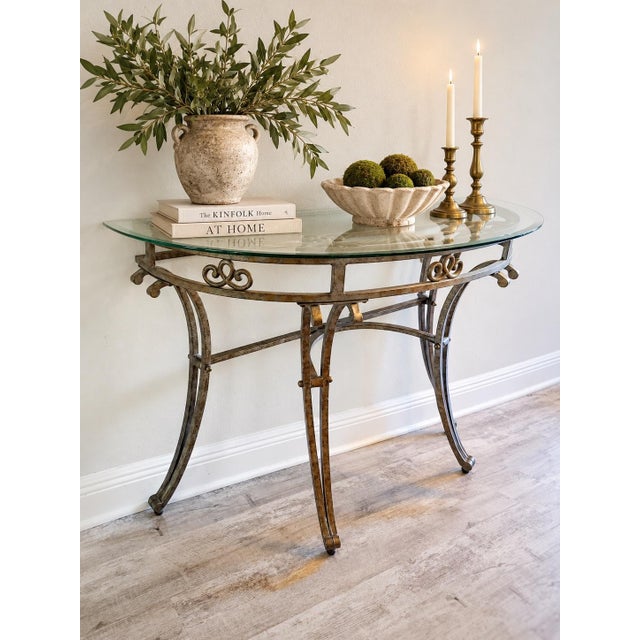 Elegant vintage glass-top console table featuring an exceptionally ornate metal base with an antiqued gilt bronze finish,...