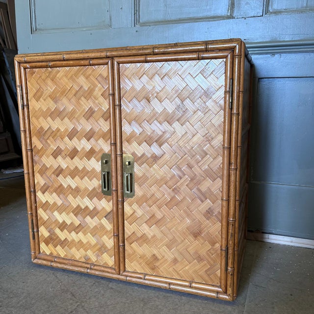 Vintage Bamboo and woven double door cabinet with brass door handles Interior is fitted with a sheld and a central divider...