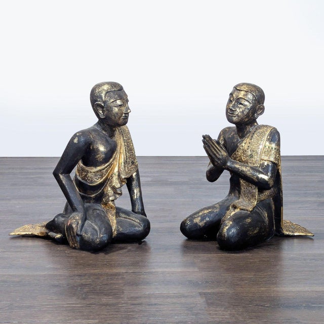 Pair of hand-carved teak Buddhist monk figures from Thailand, each depicted seated in a different pose. Finished in...