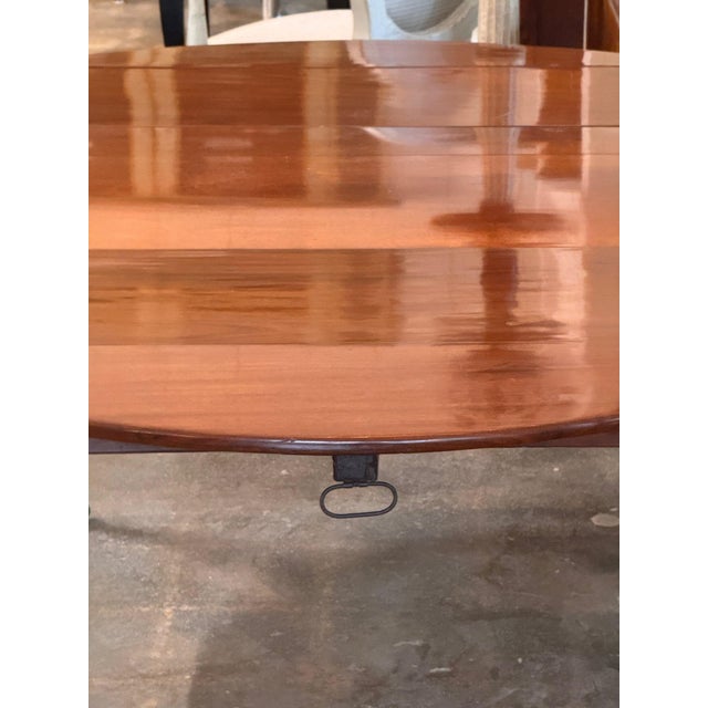 Directoire mahogany drop leaf table with an oval top and one additional leaf, on turned tapered legs ending in brass cup...
