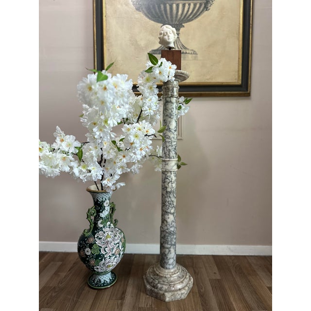 Elegant carved marble pedestal with a tall column form, round display top, and stepped octagonal base. The stone has...