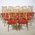 Fourteen walnut dining chairs from the 1960s with slender, tapered legs and vertical spindles in the backrest. The red...