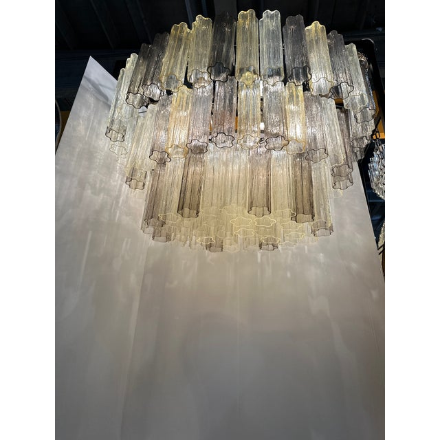 Luxury and scenographic contemporary chandelier made in Murano glass. Three levels of Murano glass “tronchi ” in champagne...