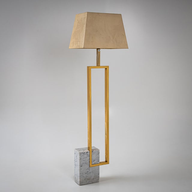 Floor lamp set on a rectangular white and grey marble base with an asymmetrically mounted brass frame. Dimensions without...