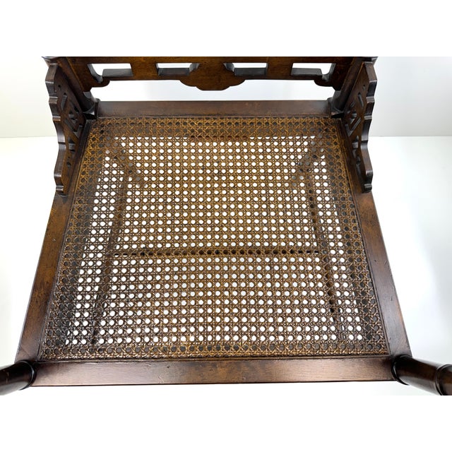 A sophisticated chinoiserie armchair rendered in richly toned faux bamboo, distinguished by its refined silhouette and...